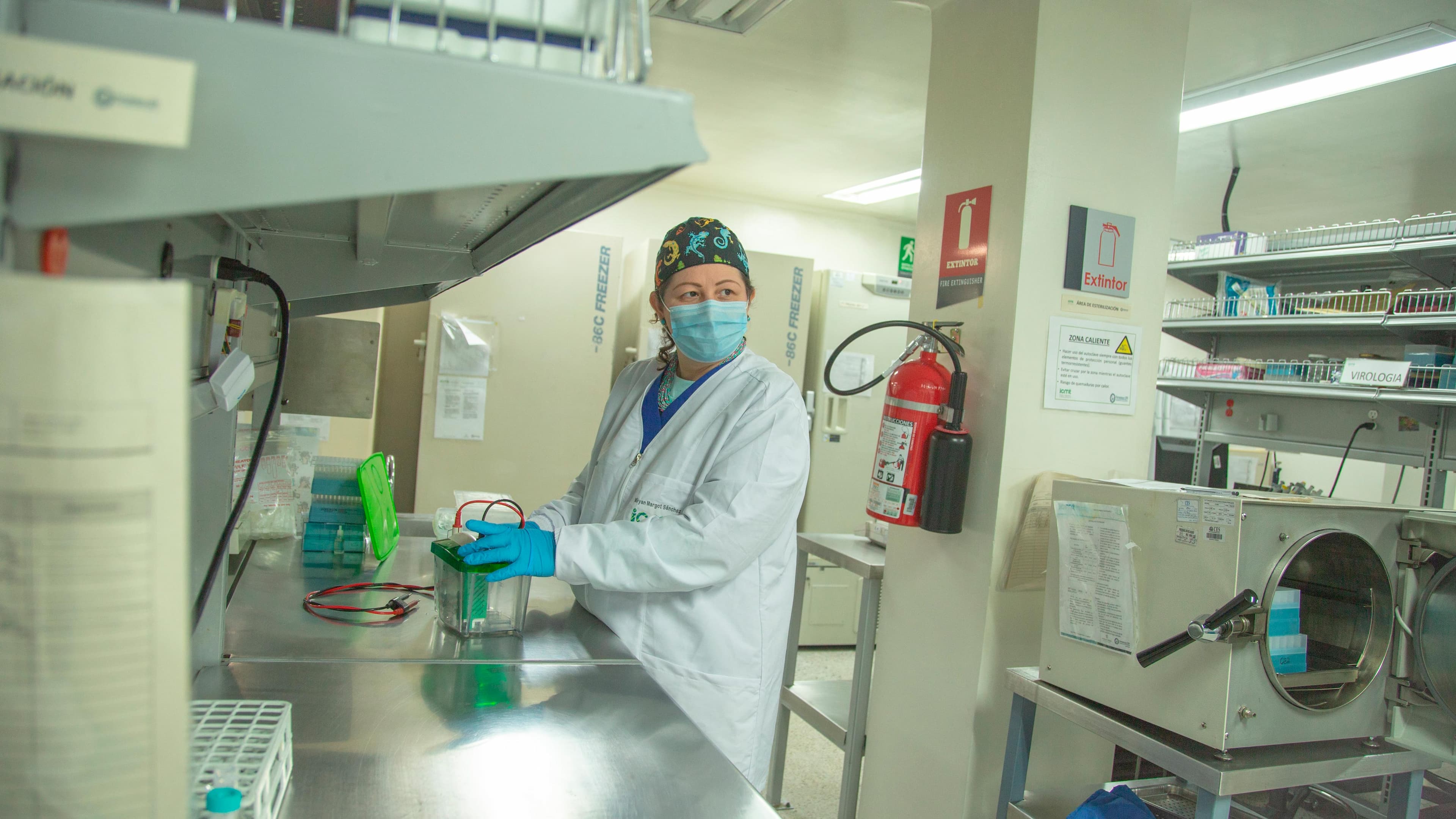 Mujer en un laboratorio, usando equipo de protección y manipulando instrumentos en un entorno clínico.