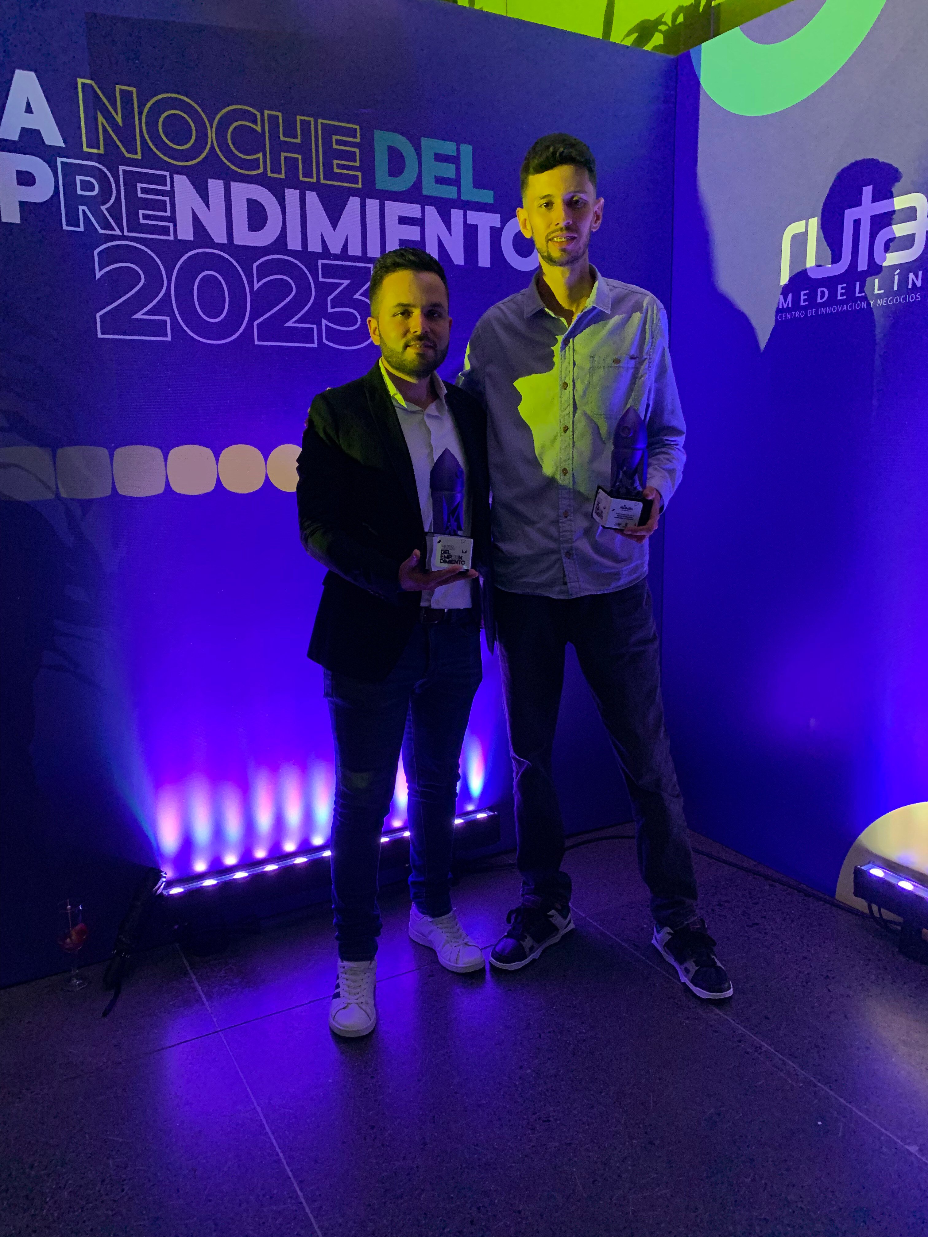 Dos hombres posan con trofeos en "La Noche del Emprendimiento 2023" organizada por Ruta N Medellín.